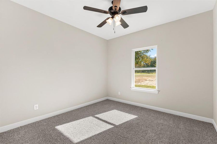 Carpeted spare room featuring baseboards and a ceiling fan