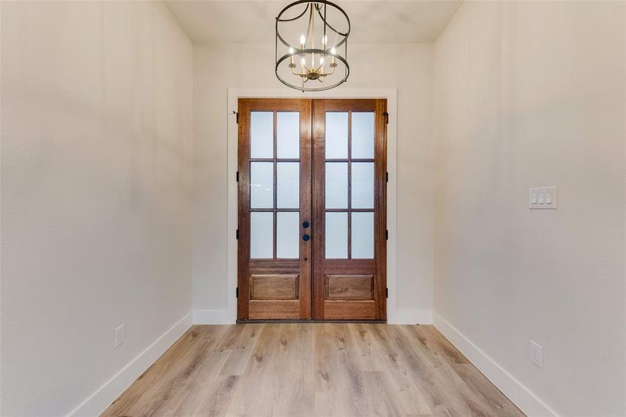 Doorway to outside with french doors, wood finished floors, and a chandelier Doorway to outside with french doors, wood finished floors, and a chandelier