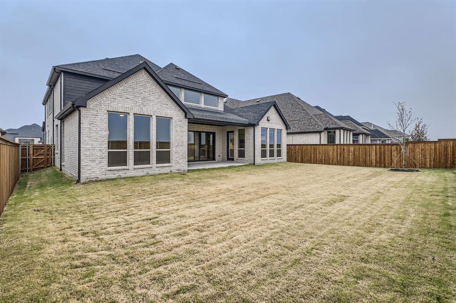 Back of house with a lawn and a patio