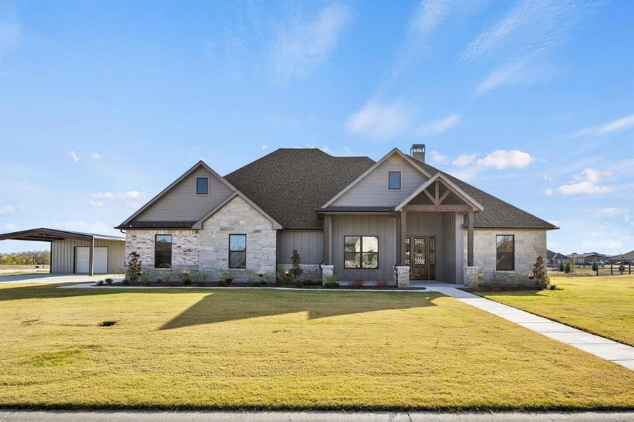 View of front of property featuring a garage, a front lawn, and an outdoor structure