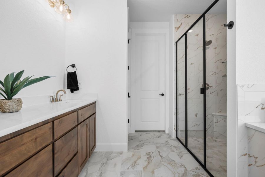 Bathroom with a marble finish shower, vanity, and light marble finish flooring