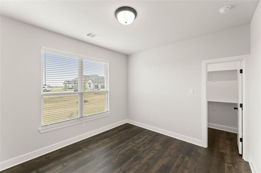 Unfurnished bedroom featuring dark wood finished floors and a spacious closet Unfurnished bedroom featuring dark wood finished floors and a spacious closet