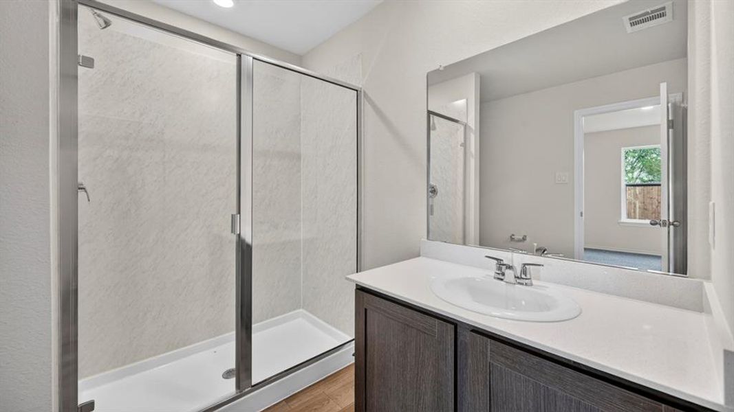 Bathroom featuring a modern vanity with a white countertop and undermount sink, brushed nickel faucet, and a large frameless mirror