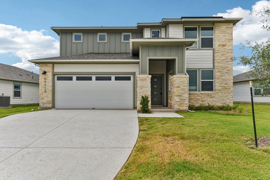 View of front facade featuring stone siding, board and batten siding, a garage, and driveway View of front facade featuring stone siding, board and batten siding, a garage, and driveway