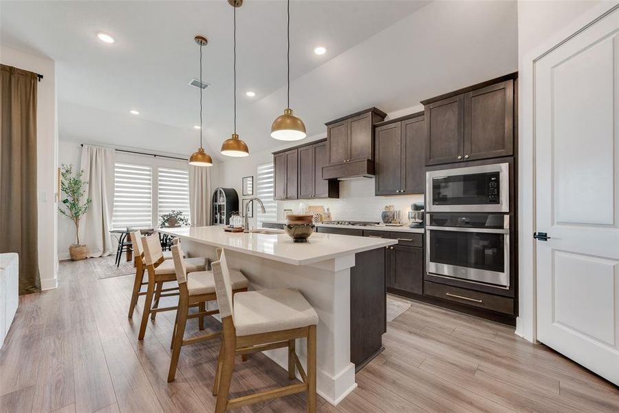 Modern kitchen featuring dark wood-finish cabinetry, stainless steel appliances, and a central island with seating
