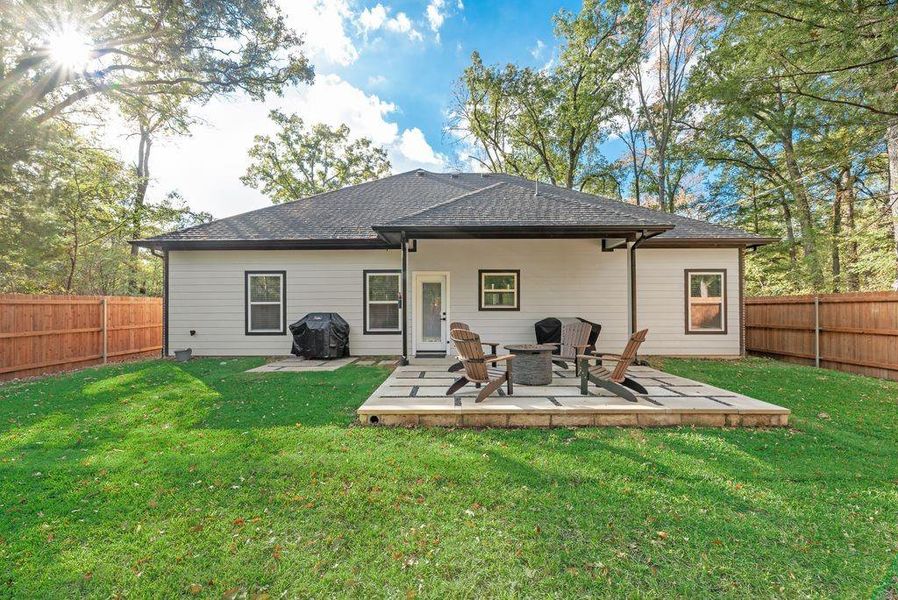 Back of house with a fenced backyard, a patio, roof with shingles, and an outdoor fire pit