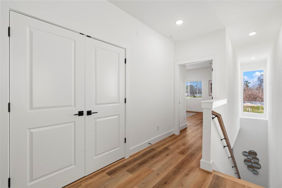 A second-floor landing with recessed lighting, premium wood flooring, and a functional layout for easy access to bedrooms and storage.