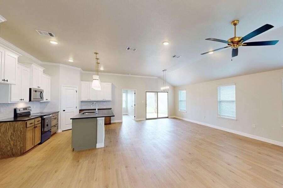 Kitchen featuring dark countertops, decorative backsplash, appliances with stainless steel finishes, open floor plan, and a kitchen island with sink