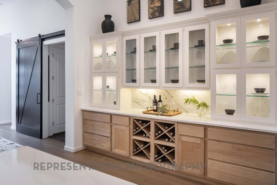 Indoor bar with arched walkways, dark wood-style flooring, a barn door, and baseboards Indoor bar with arched walkways, dark wood-style flooring, a barn door, and baseboards