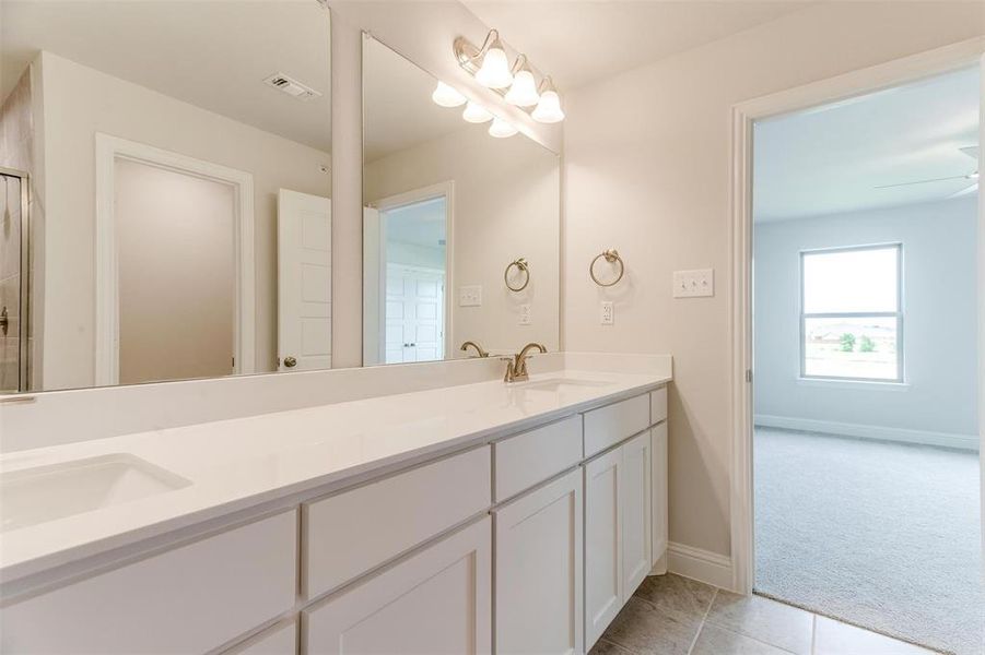Full bathroom with light tile patterned floors, light colored carpet, double vanity, and an enclosed shower