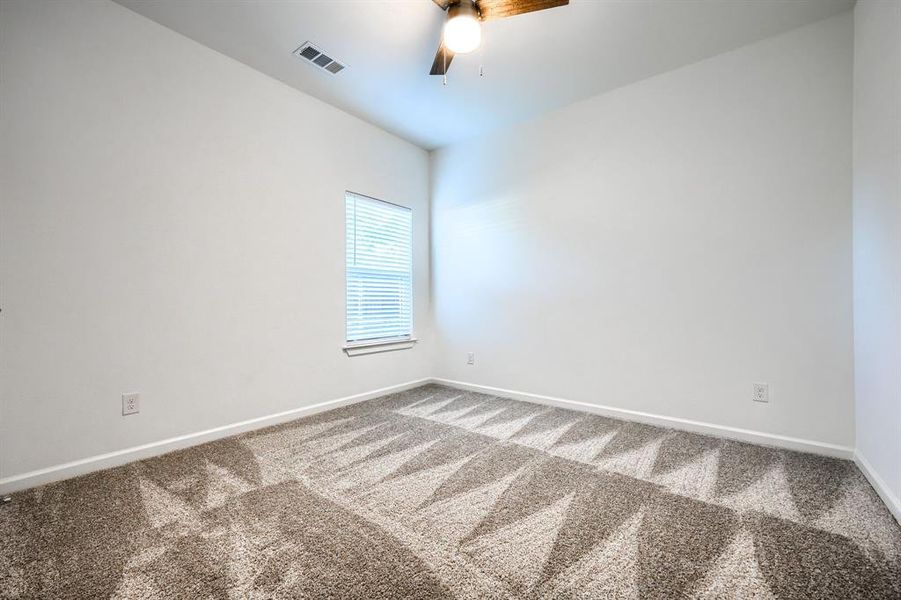 Empty room with carpet floors and a ceiling fan
