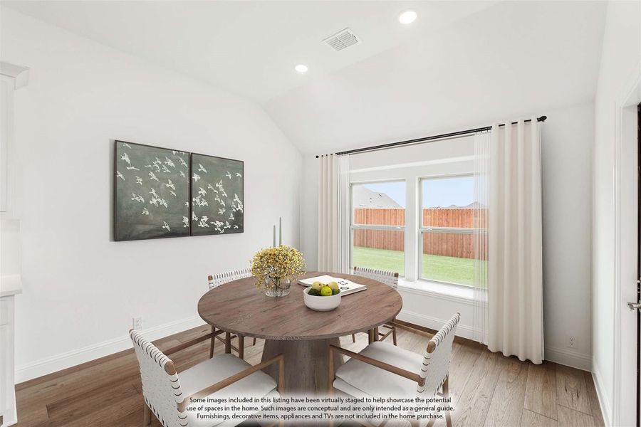 Dining area with round wood table, four chairs, vaulted ceiling, and large window with backyard view