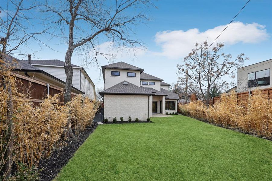 Rear view of property with a sunroom, brick siding, a patio area, and roof with shingles