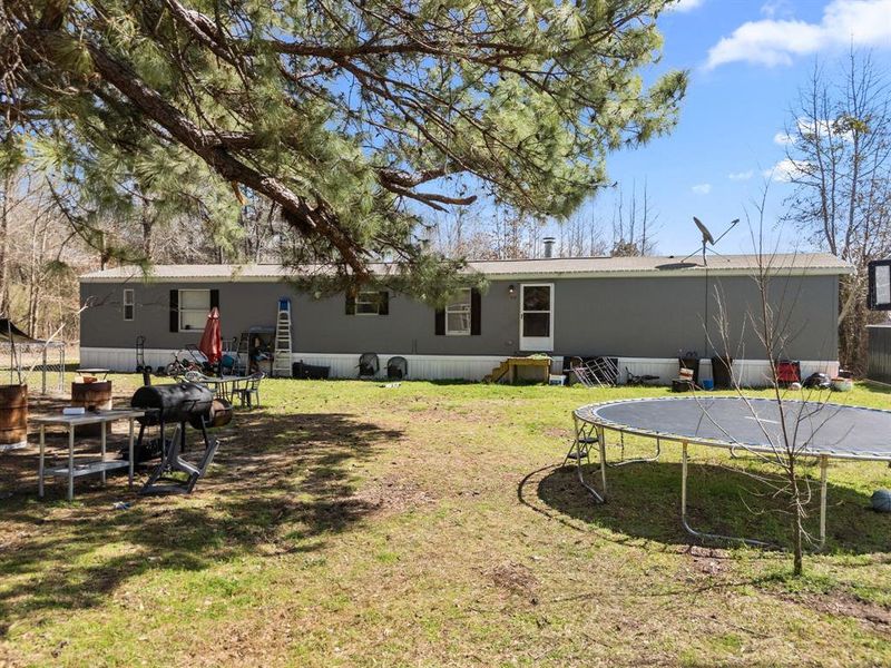 Rear view of house with entry steps, a trampoline, and a yard Rear view of house with entry steps, a trampoline, and a yard