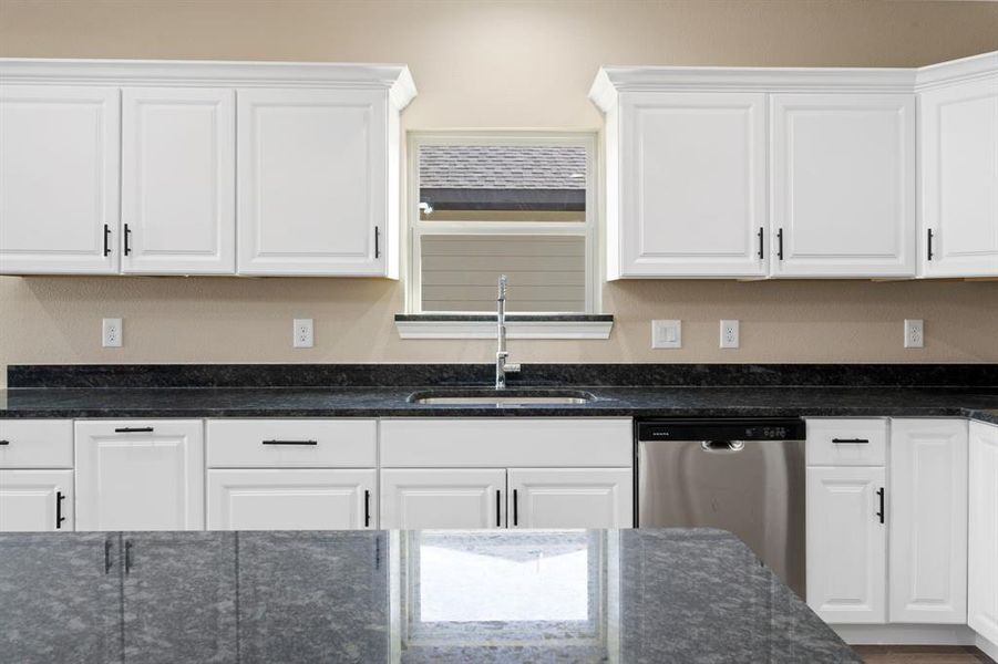 Kitchen featuring dishwasher, a sink, and white cabinetry