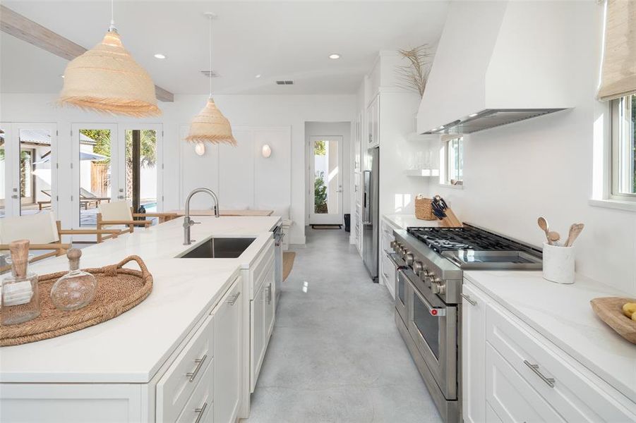 Kitchen with premium appliances, sink, hanging light fixtures, white cabinets, and ventilation hood Kitchen with premium appliances, sink, hanging light fixtures, white cabinets, and ventilation hood