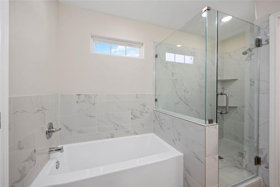 Primary bathroom with a separate soaking tub and a walk-in shower with tile surround.