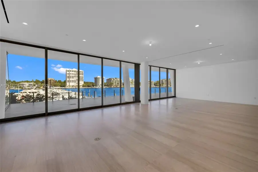 Expansive interior featuring floor-to-ceiling glass sliding doors, wood-finish flooring, recessed lighting, and a covered exterior deck