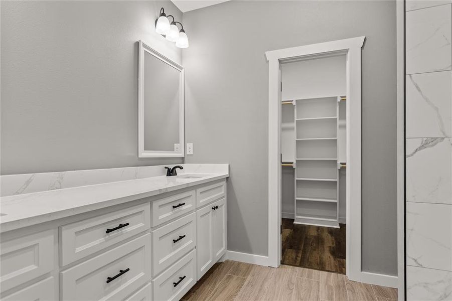 Bathroom featuring vanity, light wood-style floors, and a spacious closet