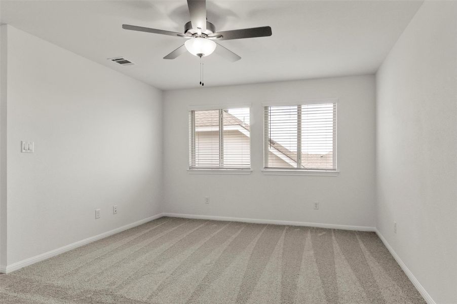 Carpeted empty room with ceiling fan and baseboards Carpeted empty room with ceiling fan and baseboards