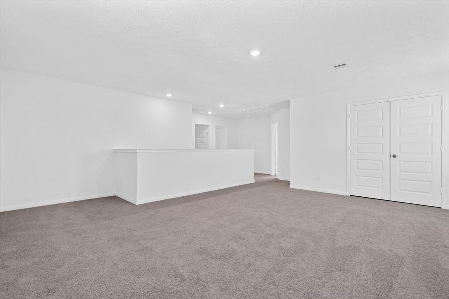 Another perspective of the Loft, showcasing the staircase, linen closet, and hallway leading to the secondary bedrooms.