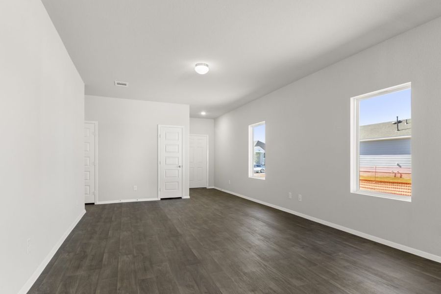 Image of a living room area with dark brown vinyl flooring, light grey walls and windows