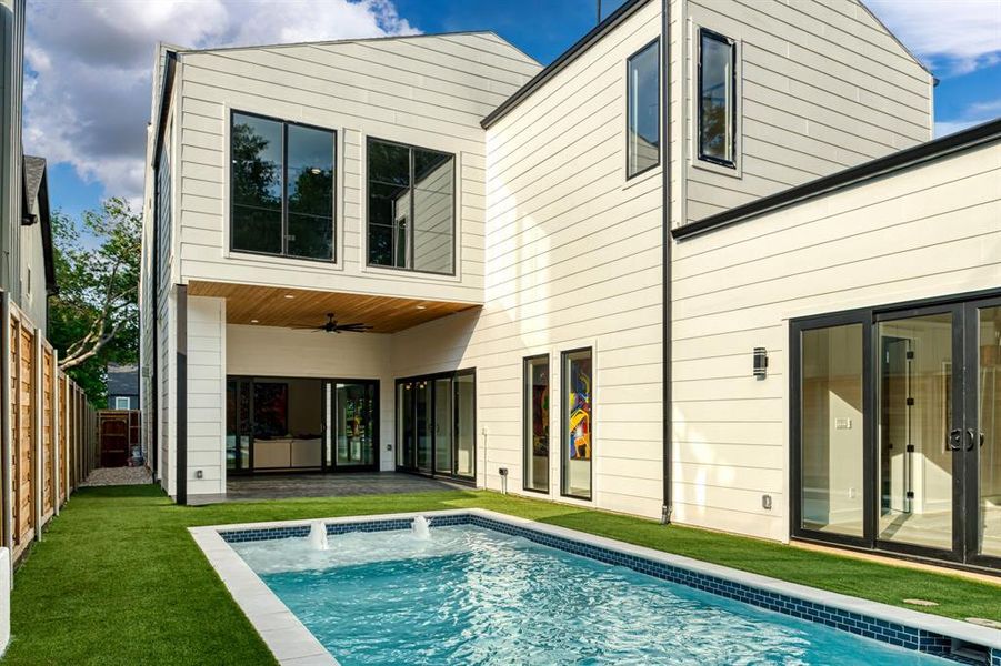 Rear view of property with pool water feature, ceiling fan, and a fenced in pool