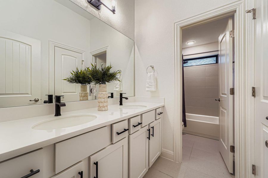 Bathroom with double vanity, light tile patterned floors, and shower / tub combo Bathroom with double vanity, light tile patterned floors, and shower / tub combo