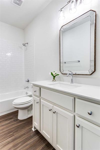 Full bathroom featuring tiled shower / bath combo, wood-type flooring, vanity, and toilet