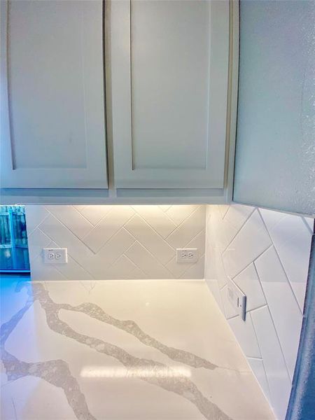 White cabinets, Marcella Quartz, and white herringbone subway tile backsplash with undermount lighting