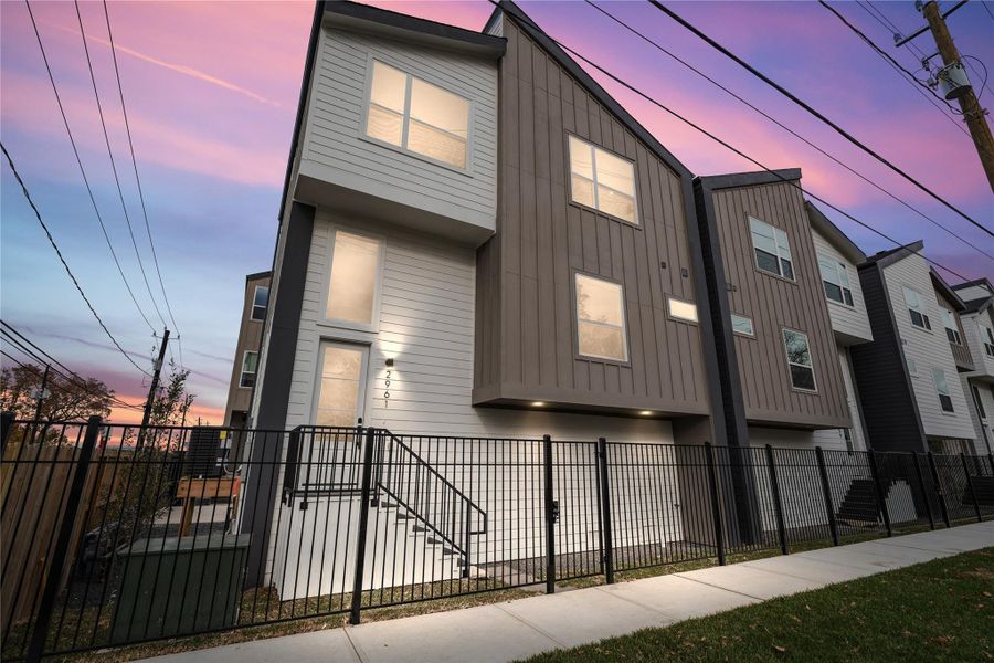 *This is the model unit* Clean lines define the striking curb appeal of this gated corner home. With a dramatic roofline, vertical siding accents, and large windows that glow at dusk, this elevation blends contemporary design with a warm, welcoming presence in the heart of the city.