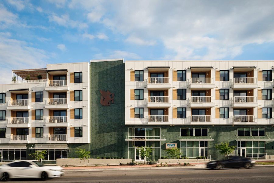 A modern multi-story residential building displays clean architectural lines and private balconies under blue skies. A modern multi-story residential building displays clean architectural lines and private balconies under blue skies.