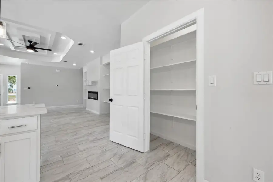 Kitchen with recessed lighting, white cabinets, ceiling fan, light countertops, and a glass covered fireplace Kitchen with recessed lighting, white cabinets, ceiling fan, light countertops, and a glass covered fireplace