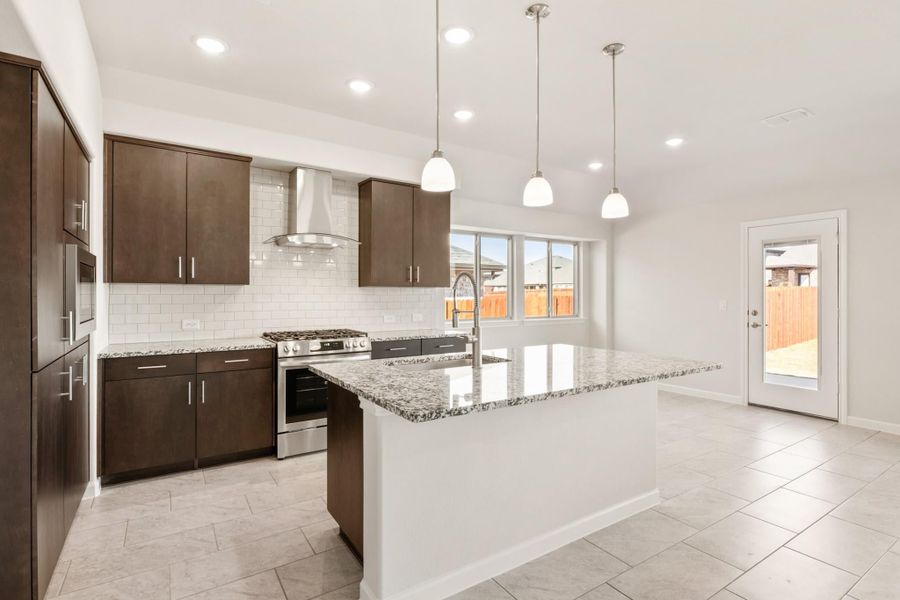 Kitchen with dark brown cabinets, granite island, stainless steel range, and white subway tile backsplash Kitchen with dark brown cabinets, granite island, stainless steel range, and white subway tile backsplash