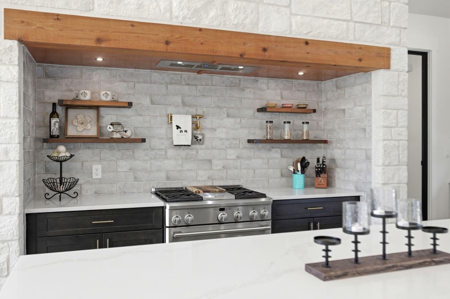 A striking rustic wooden mantle frames the professional range and tiled backsplash area.