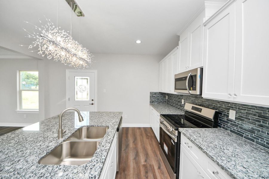 The kitchen is a bright, welcoming space where modern design meets everyday practicality. A beautiful pendant light fixture draws the eye, while ample counter space and cabinetry make it perfect for preparing meals and gathering with family and friends - (representation photo).