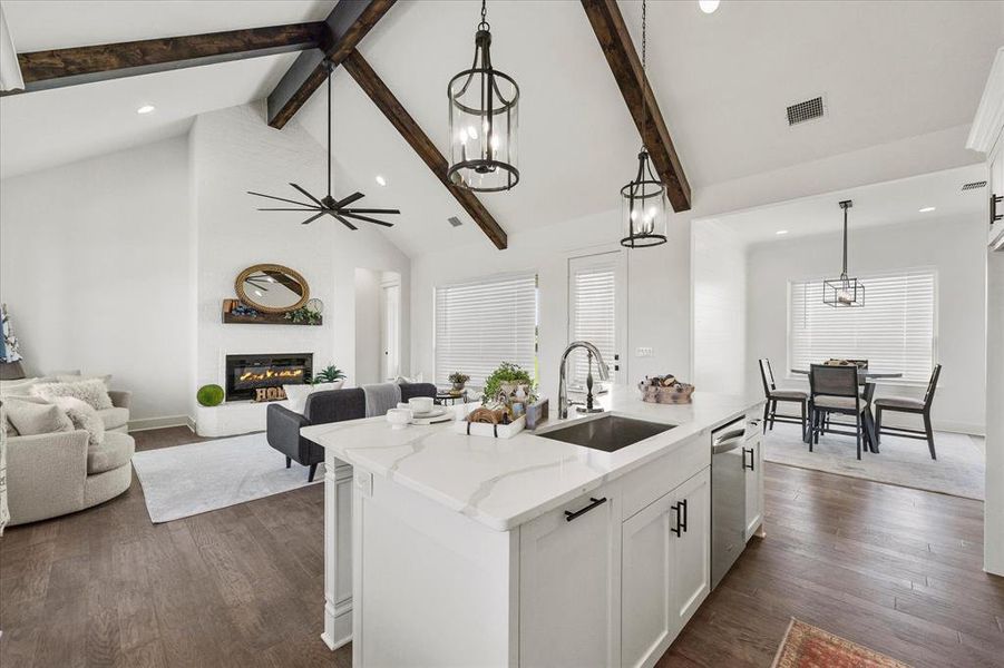 Kitchen with a fireplace, high vaulted ceiling, a kitchen island with sink, sink, and dark hardwood / wood-style floors