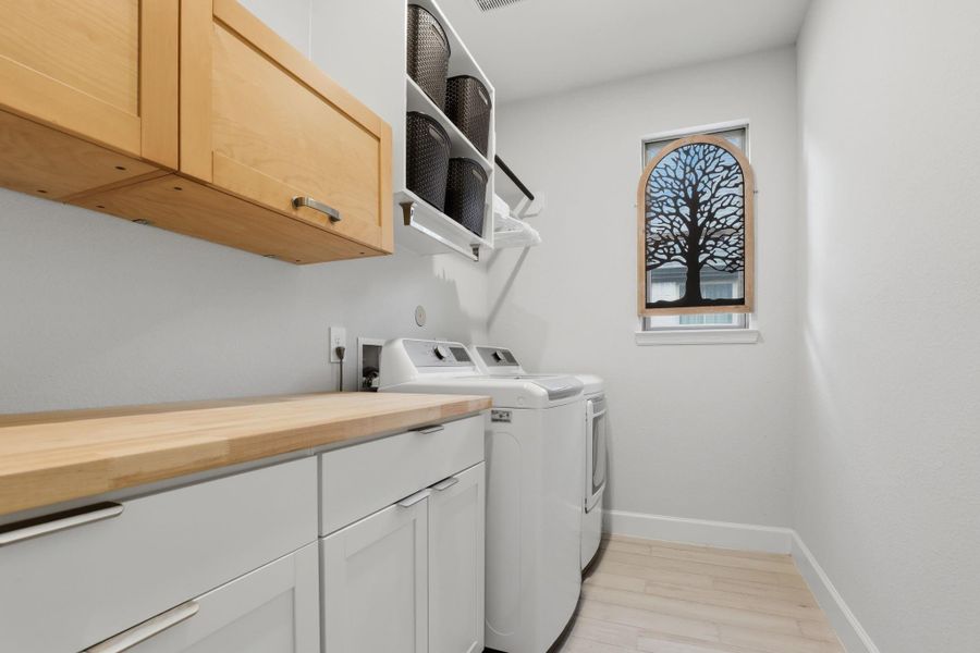 This functional utility space features homeowner-built upper cabinetry, a matching butcher block folding counter, and open sorting shelves.