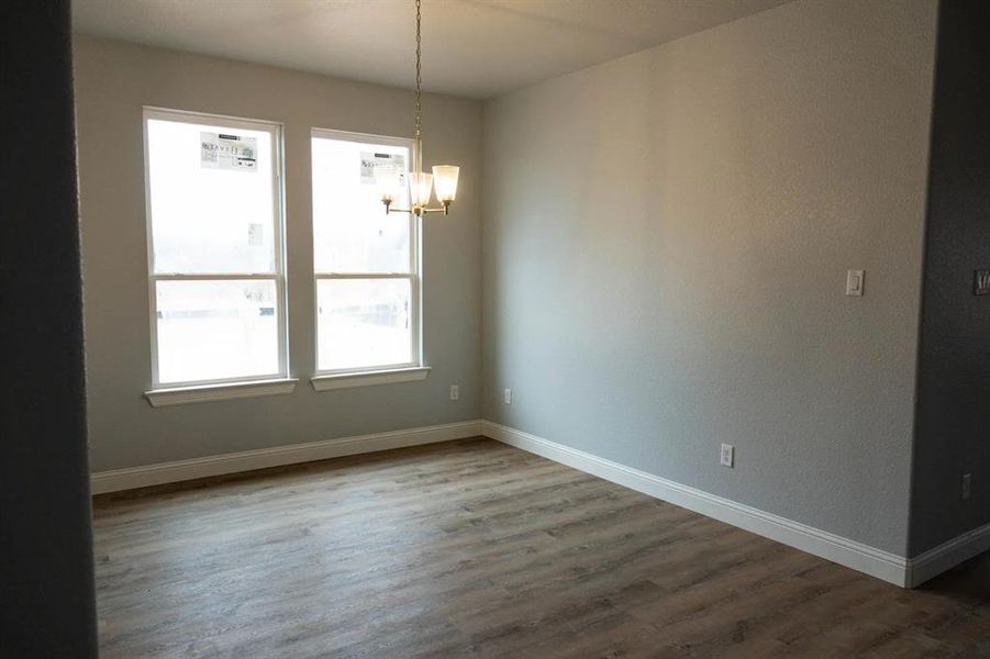 Spare room with a chandelier and dark hardwood / wood-style flooring