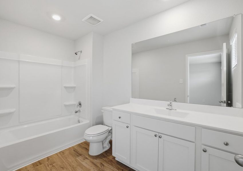 Primary bathroom featuring a tub/shower combination and a white vanity with cultured marble countertop.