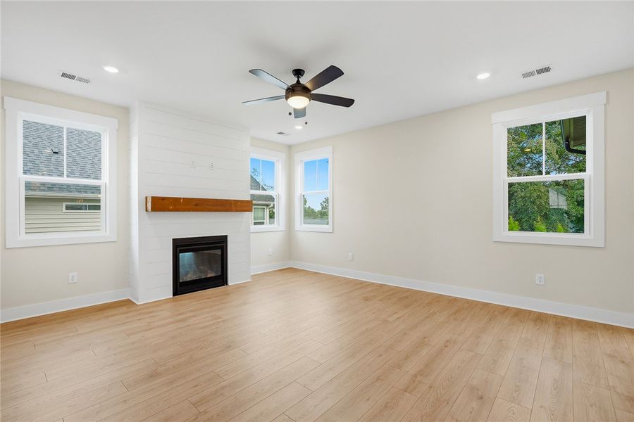 Warm wood flooring and a modern fireplace anchor t