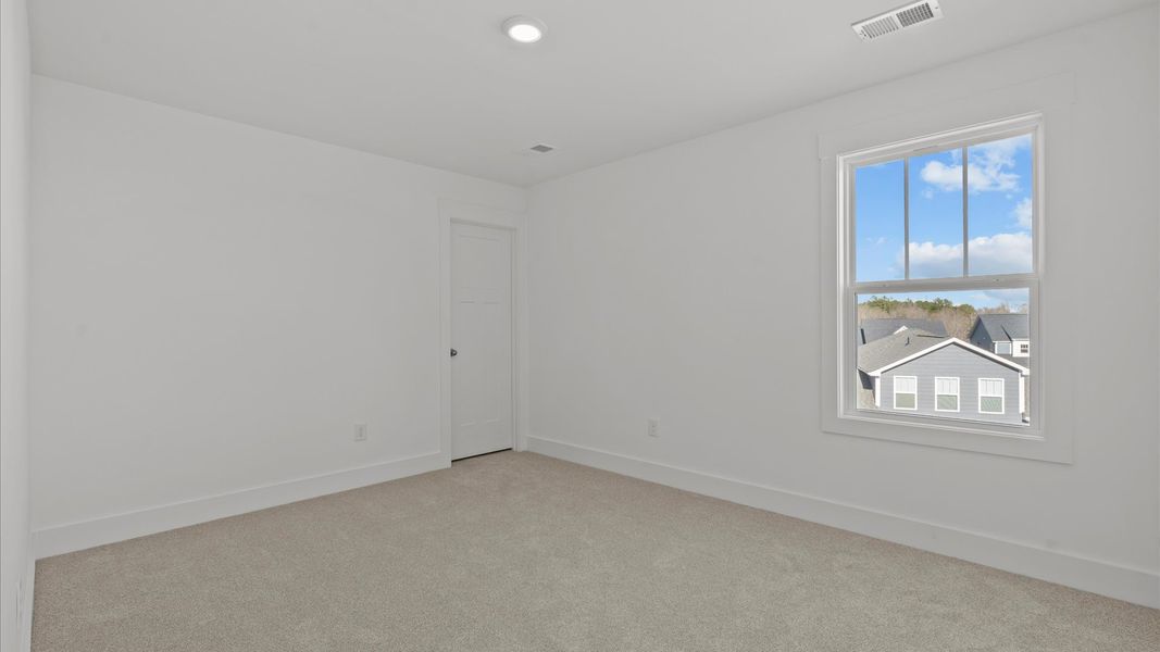 Elegant carpeted bedroom with walk-in closet and wall-to-wall windows offering natural brightness