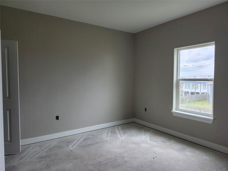This is a bedroom with neutral-painted walls and a large window letting in natural light.
