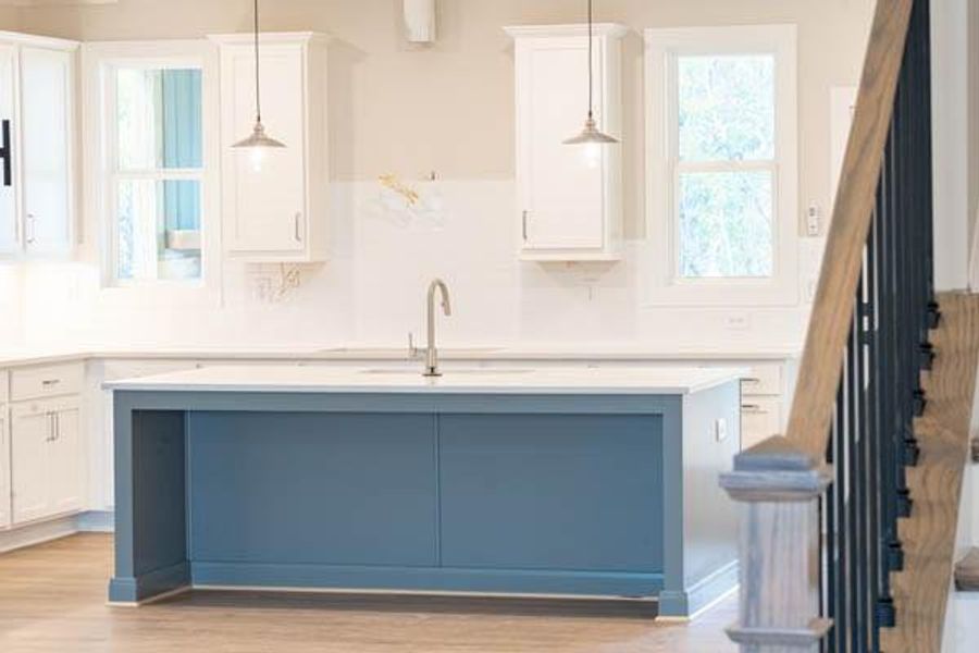 Kitchen with sink, light hardwood / wood-style flooring, a kitchen island with sink, hanging light fixtures, and white cabinets Kitchen with sink, light hardwood / wood-style flooring, a kitchen island with sink, hanging light fixtures, and white cabinets