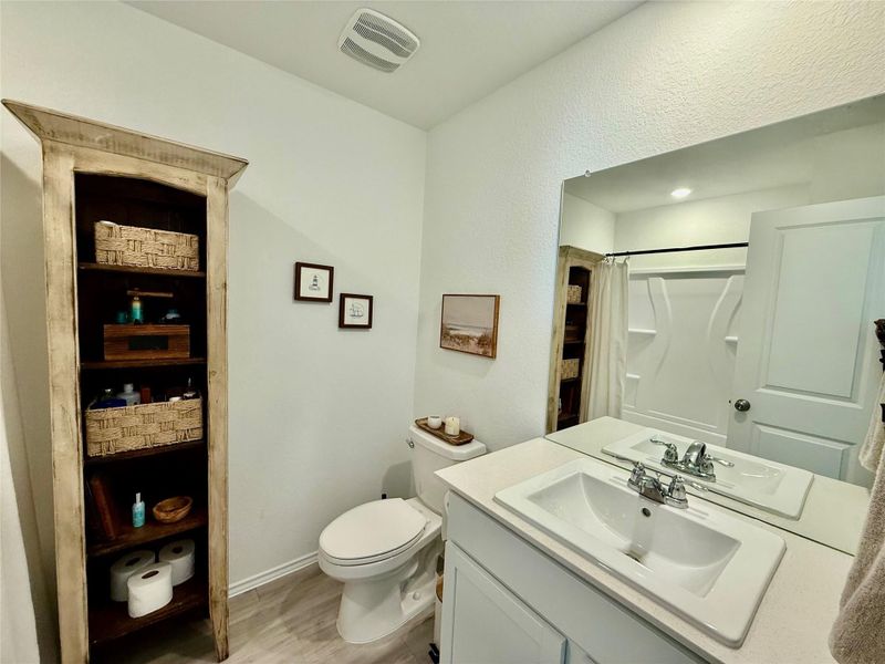 Full bath with vanity, a shower with shower curtain, and light wood-style floors