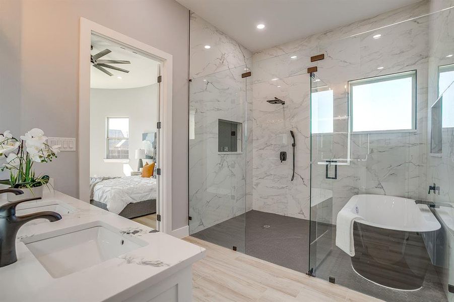Bathroom featuring healthy amount of natural light, ensuite bathroom, a freestanding tub, double vanity, and recessed lighting