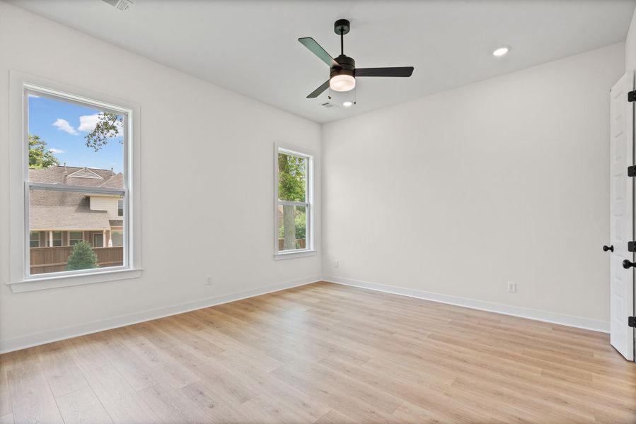 Bright room featuring wood-finish flooring, white walls, and a contemporary ceiling fan with integrated lighting Bright room featuring wood-finish flooring, white walls, and a contemporary ceiling fan with integrated lighting