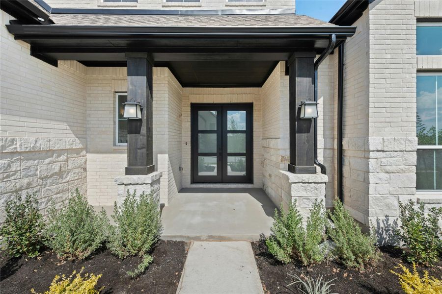 View of exterior entry featuring covered porch, brick siding, and roof with shingles View of exterior entry featuring covered porch, brick siding, and roof with shingles