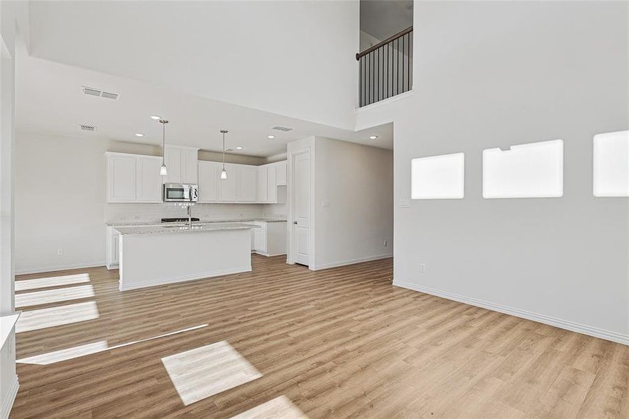 Unfurnished living room featuring light wood-style floors, a high ceiling, and recessed lighting