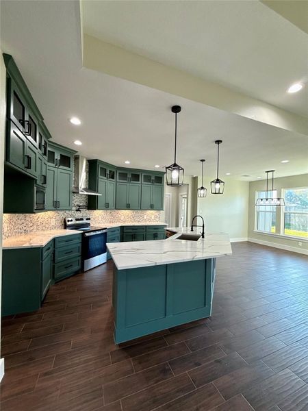 This modern kitchen features elegant dark green cabinetry, a spacious island with a white countertop, and stylish pendant lighting. The open layout with wood-look flooring and ample natural light creates a warm, inviting space perfect for cooking and entertaining. This modern kitchen features elegant dark green cabinetry, a spacious island with a white countertop, and stylish pendant lighting. The open layout with wood-look flooring and ample natural light creates a warm, inviting space perfect for cooking and entertaining.
